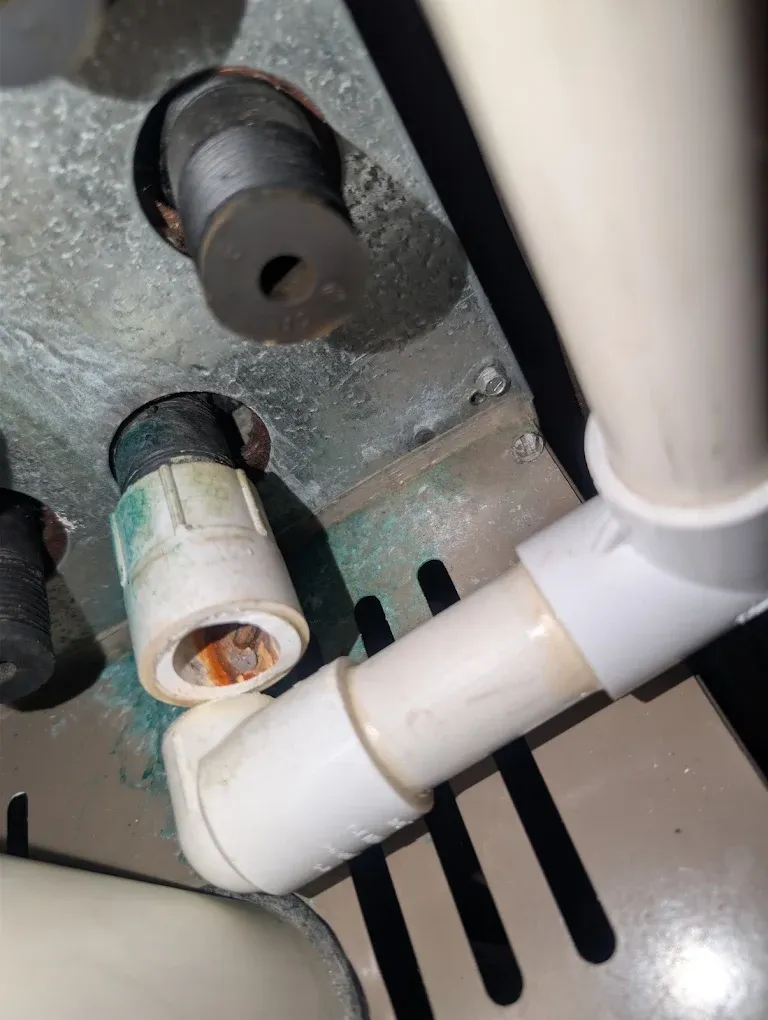 Corroded metal pipe outlets and a PVC coupler with rust in the fitting.