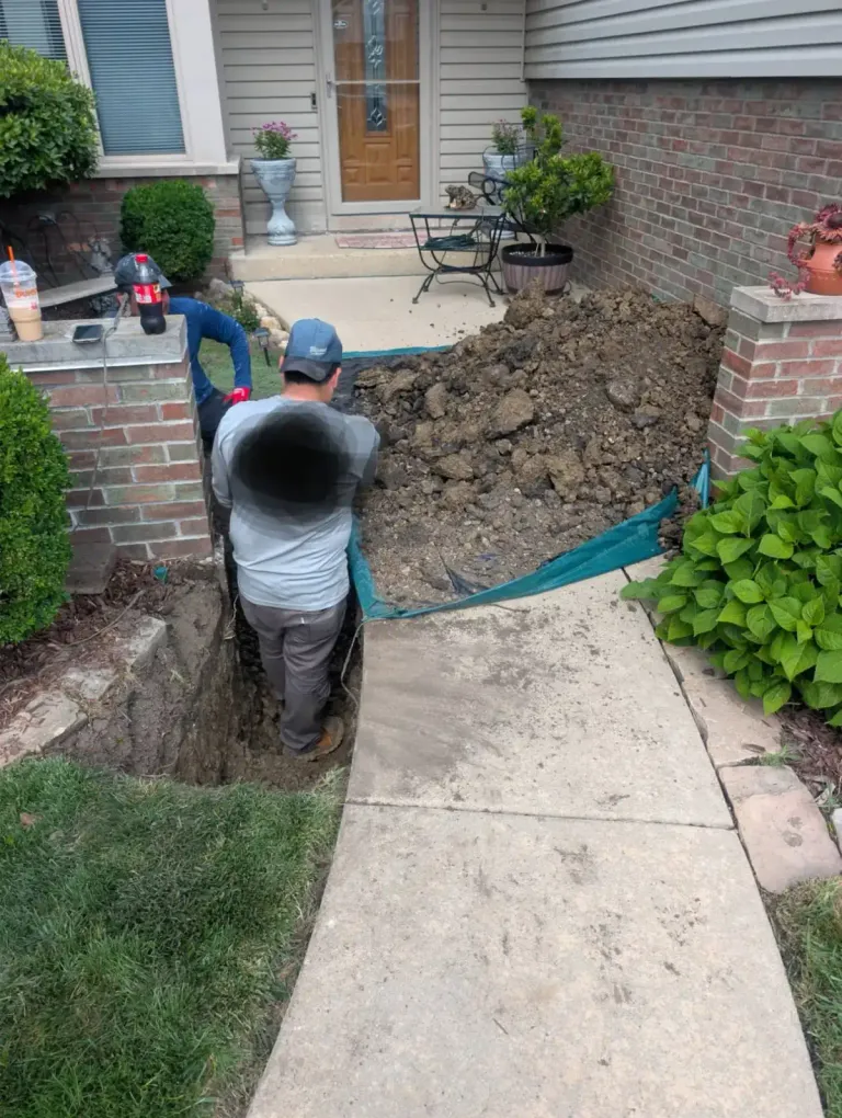 Workers excavating a trench along a residential walkway.