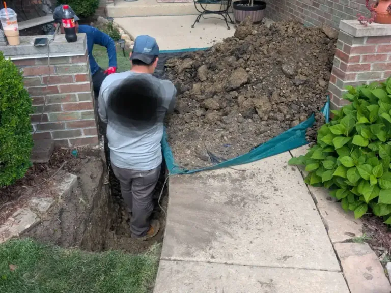Workers excavating a trench along a residential walkway.