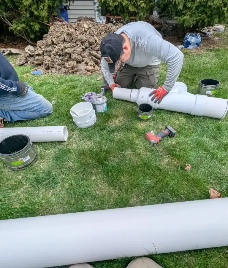 Workers prepping PVC pipe on the grass.