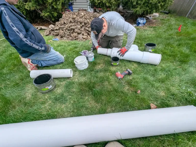 Worker assembling white pipe outdoors.