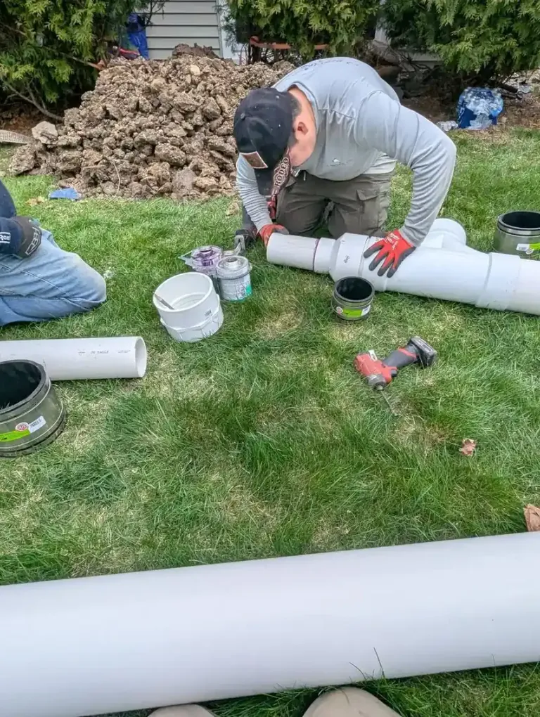 Worker assembling white pipe outdoors.