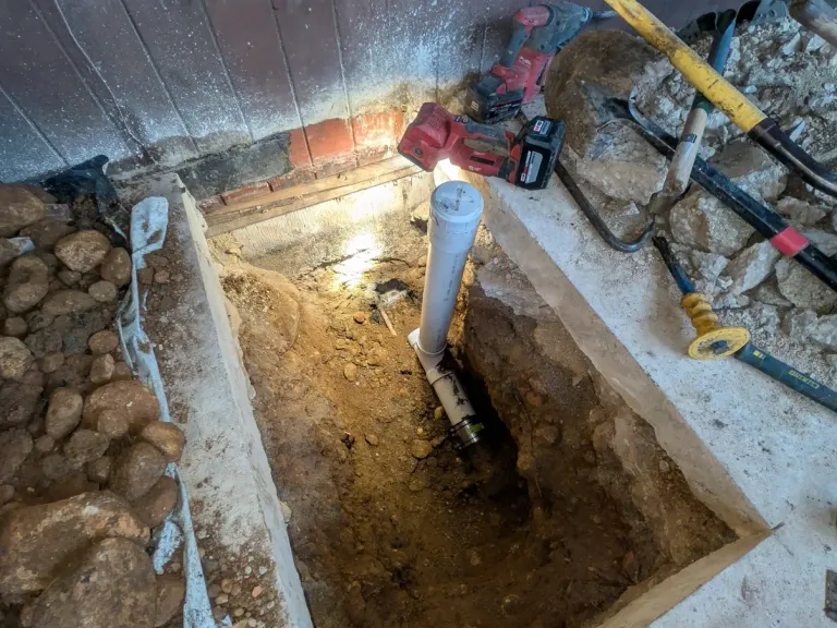 Deep trench with exposed pipe.