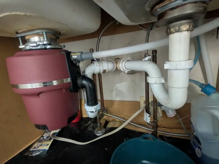 Leaking PVC under a sink next to a garbage disposal.