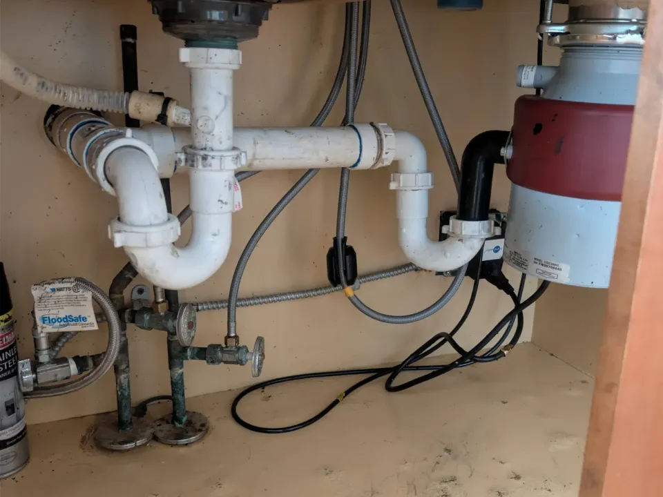 Under-sink pipes next to a garbage disposal.