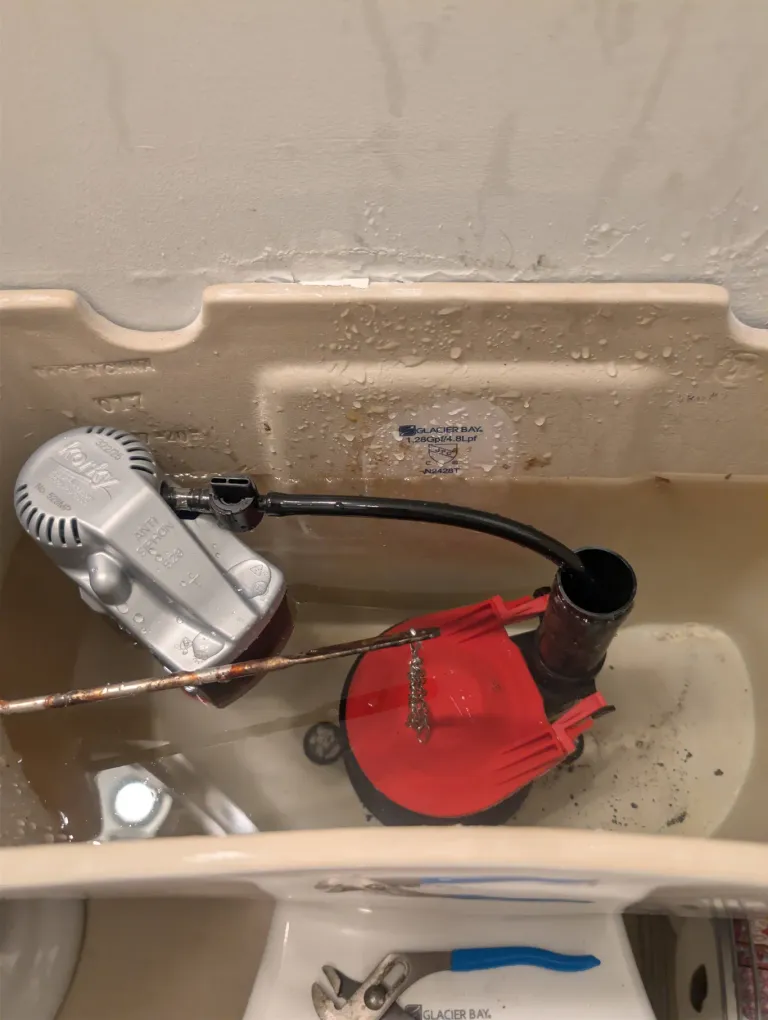 A toilet tank with the lid off.
